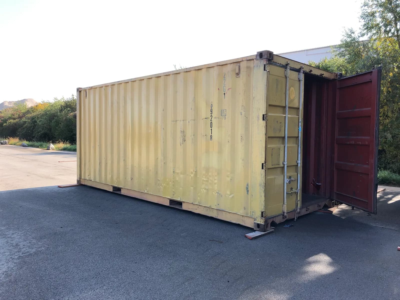 Gebrauchter 20-Fuß-Container in Gelb mit geöffneter Tür und sichtbaren Gebrauchsspuren