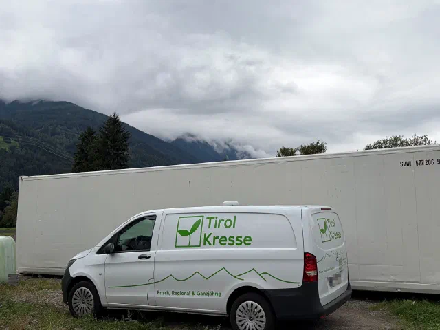 Lieferwagen von Tirol Kresse vor dem weißen 40-Fuß-Kühlcontainer in Telfs