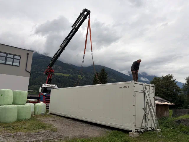 Ein LKW-Kran setzt den Kühlcontainer am Standort ab